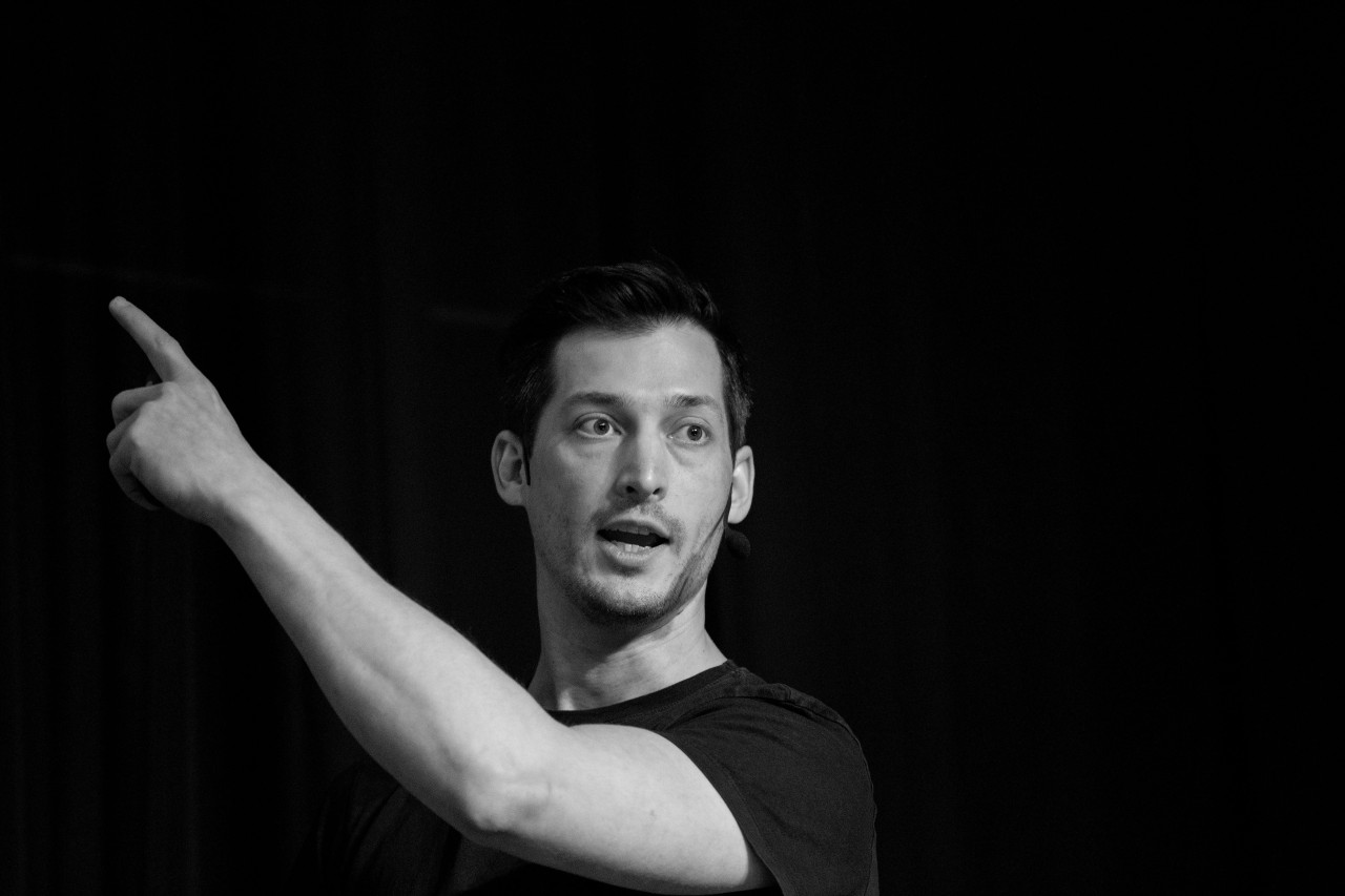 Stephan Rüb speaking on stage, gesturing to an audience